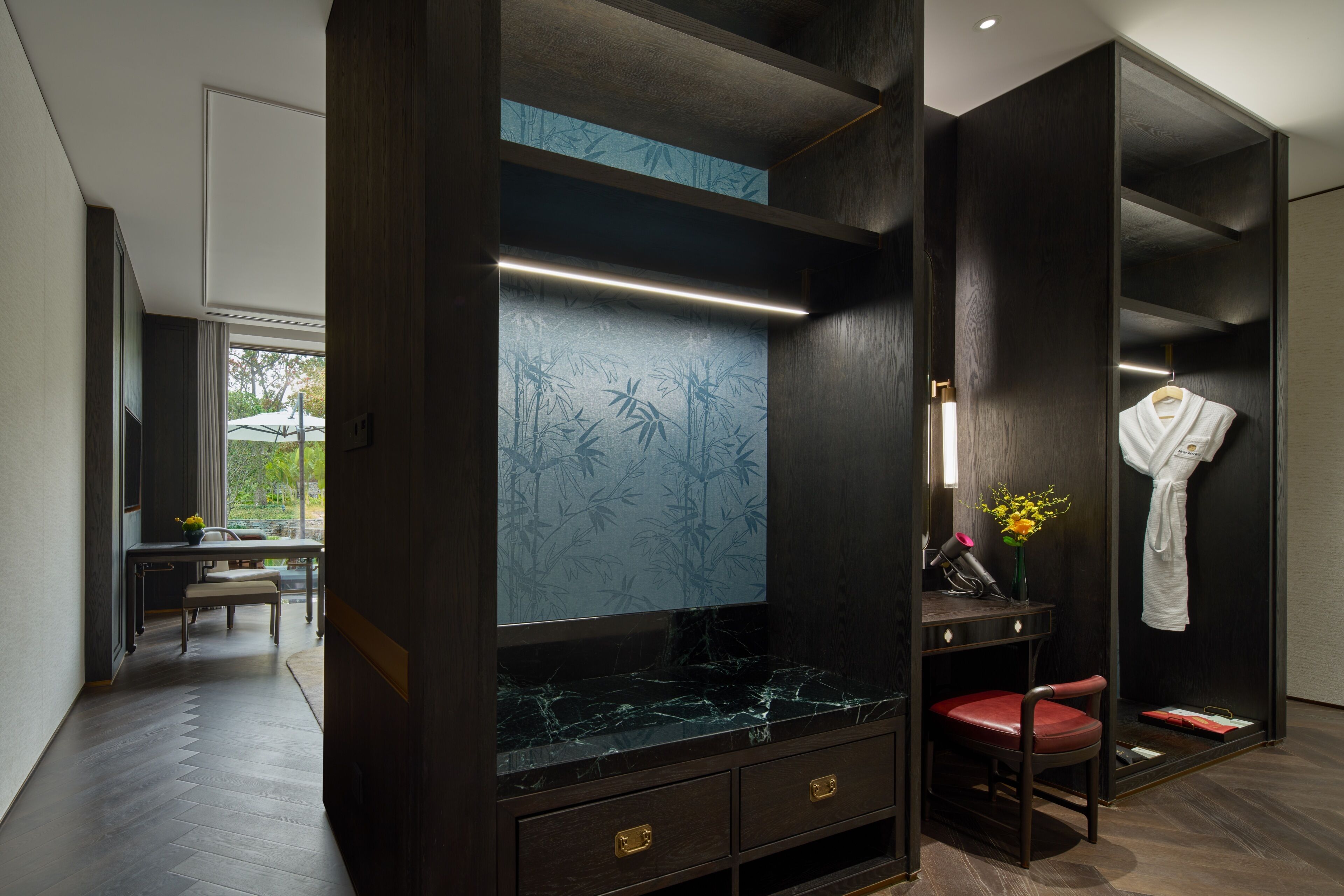 A modern bathroom with a vanity, a mirror, a robe, and a bench.