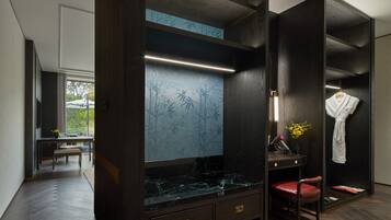A modern bathroom with a vanity, a mirror, a robe, and a bench.