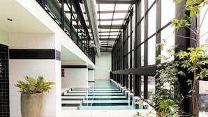 A modern indoor space with a staircase, potted plants, and large windows. - Iconic Queensbridge New Designer Suite with Heated Pool, Gym, Sauna, and Steam (Melbourne)