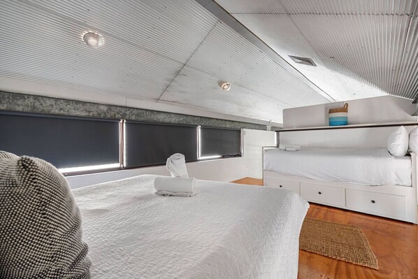 A modern, well-lit room with a large bed, a smaller bed, and a seating area. - Hidden Zen - A South Freo Retreat (South Fremantle)