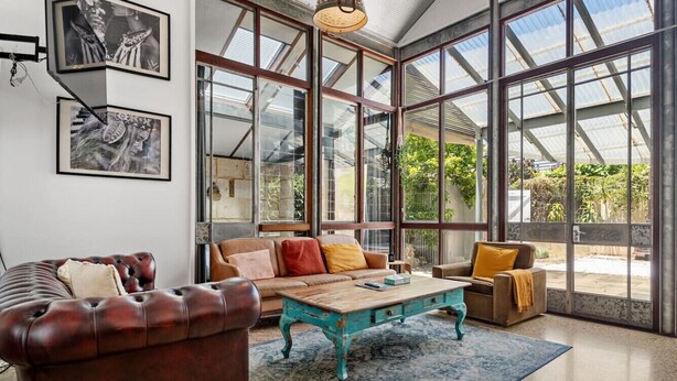 Ein geräumiges Wohnzimmer mit einer großen Glaswand, einem Ledersofa und einem Holztisch.