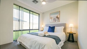 Hotellihuone, jossa on suuri sänky, kaksi yöpöytävalaisinta, taulu seinällä ja näkymä ikkunasta.