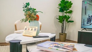 Vastaanottotiski, jossa on tervetulotoivotus, maljakko kukkineen, viherkasvi ja lehti pöydällä.