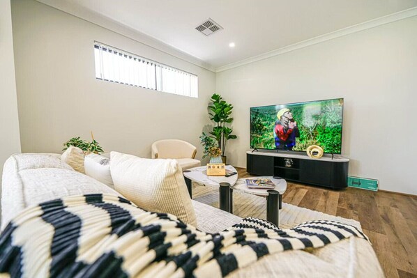 En moderne stue med sofa, sofabord, fjernsyn og en plante.