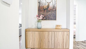 Um armário de madeira com um vaso de flores e um quadro com a imagem de um veado na parede.