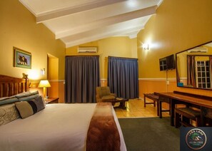 A hotel room with a bed, a desk, a chair, a TV, and curtains. - Majuba Lodge By Leba Lane (Newcastle)