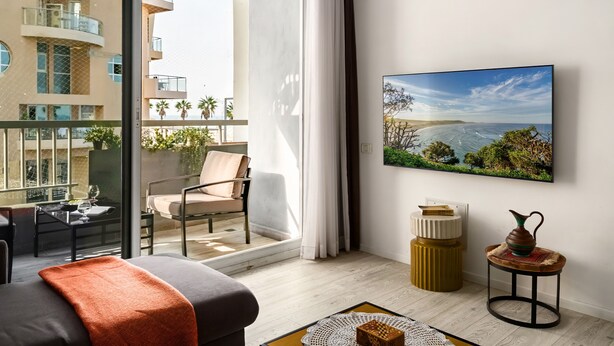 Un salon moderne avec un balcon, une grande peinture et une table basse.