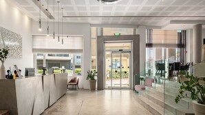 Un espace d’accueil moderne comprenant un comptoir de réception, des sièges et un escalier menant à un niveau supérieur.