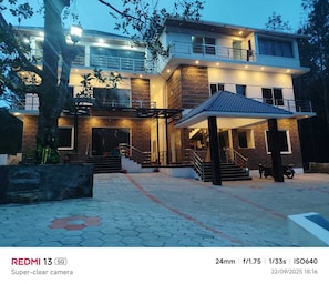 A modern two-story house with a spacious entrance, a covered patio, and a staircase leading to the upper floor. - BKP Jungle Resorts (Yercaud)