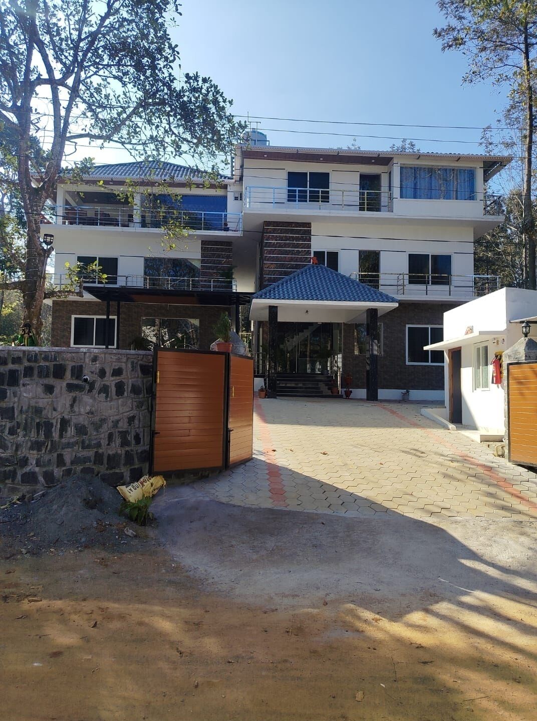 Una casa moderna de dos pisos con un porche cubierto y un muro de piedra.