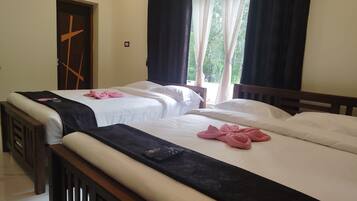 Een hotelkamer met twee bedden, een houten hoofdbord, een kruis op de deur en een raam met gordijnen.