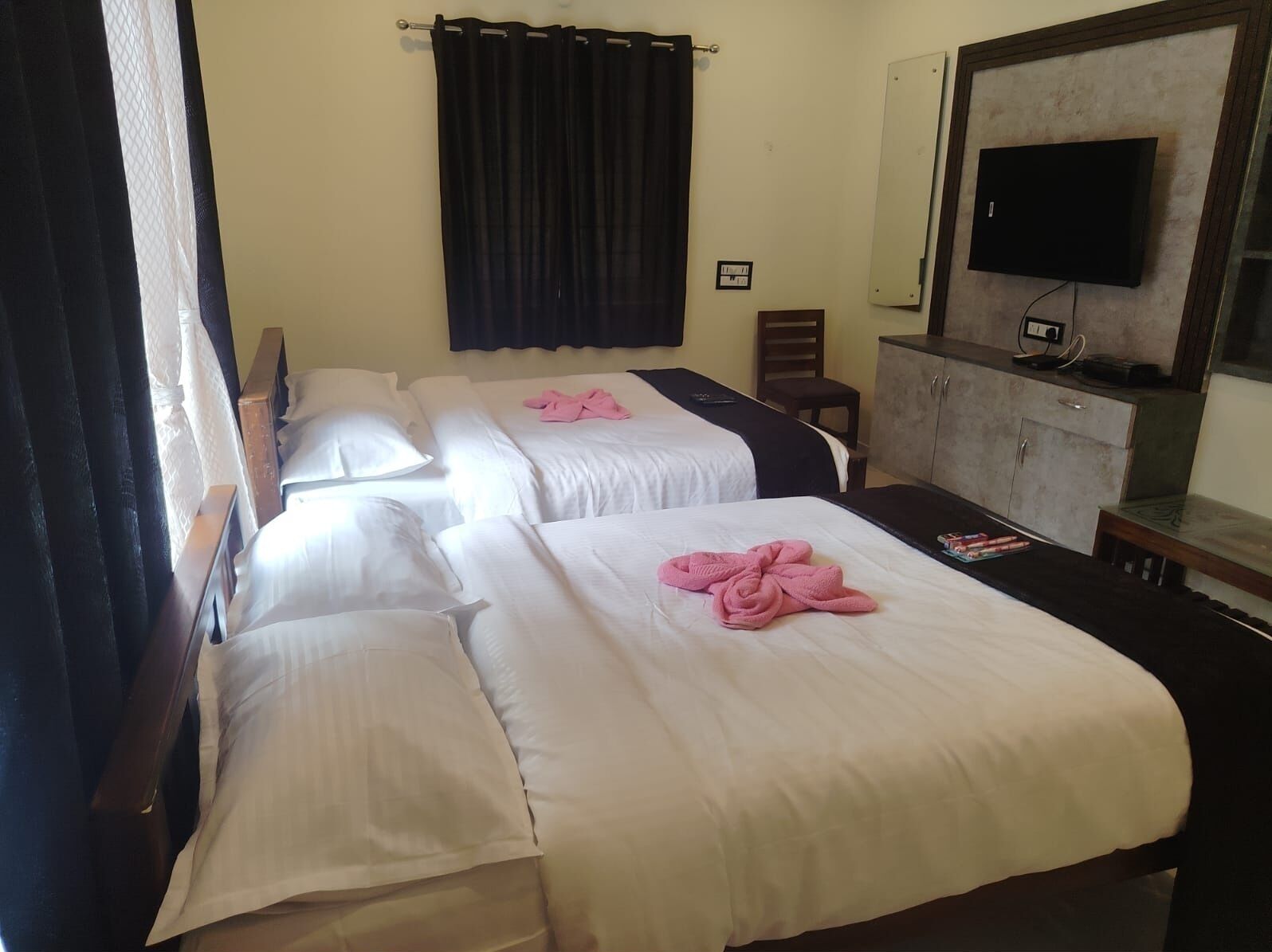 Habitació d'hotel amb dos llits, una televisió, un armari i una cadira.