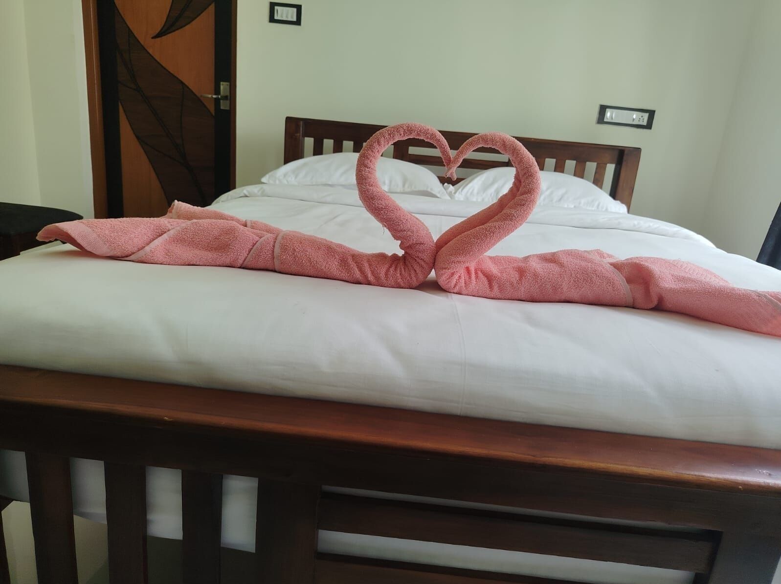 A bed with a heart-shaped towel arrangement.