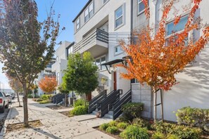 A residential building with a modern design, featuring a central staircase, a small garden area, and a clear sky. - Bright 3BR/3BA San Jose Townhome | Great Location (San Jose)
