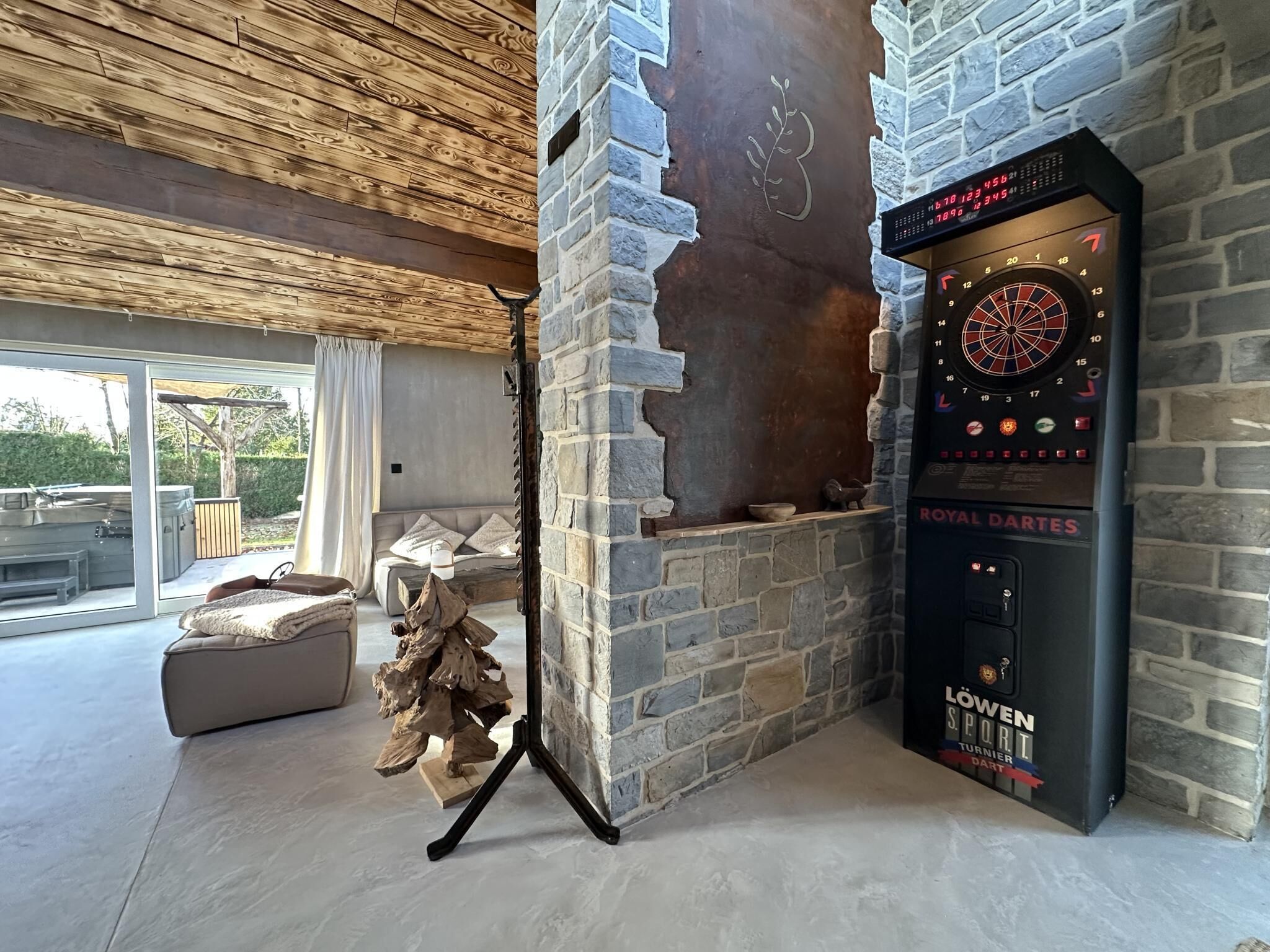 Una sala de estar moderna con chimenea de piedra, un dardo y un rincón de estar acogedor.