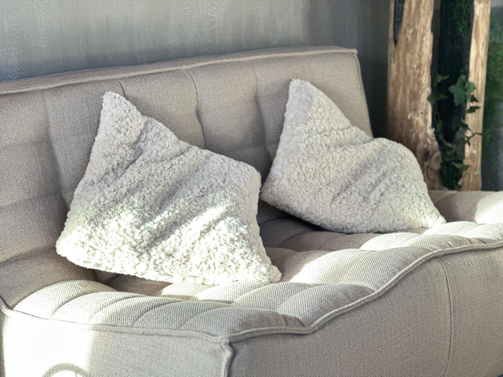 En beige soffa klädd i tyg, med två dekorativa kuddar.