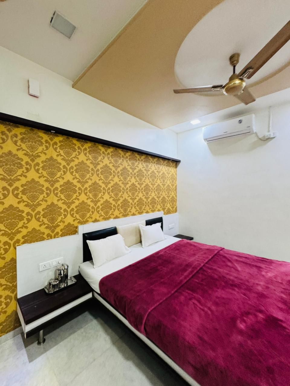 A hotel room with a bed, bedside table, and a ceiling fan.