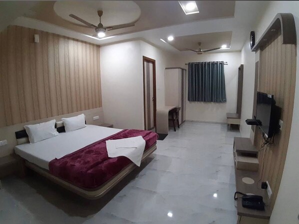 A bedroom with a bed, a ceiling fan, a TV, and a bathroom with a shower. - Hotel A1 (Morshi)