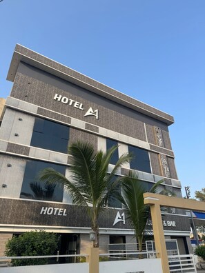 A modern hotel building with a prominent 'HOTEL' sign on the facade, a bar area, and palm trees in front. - Hotel A1 (Morshi)
