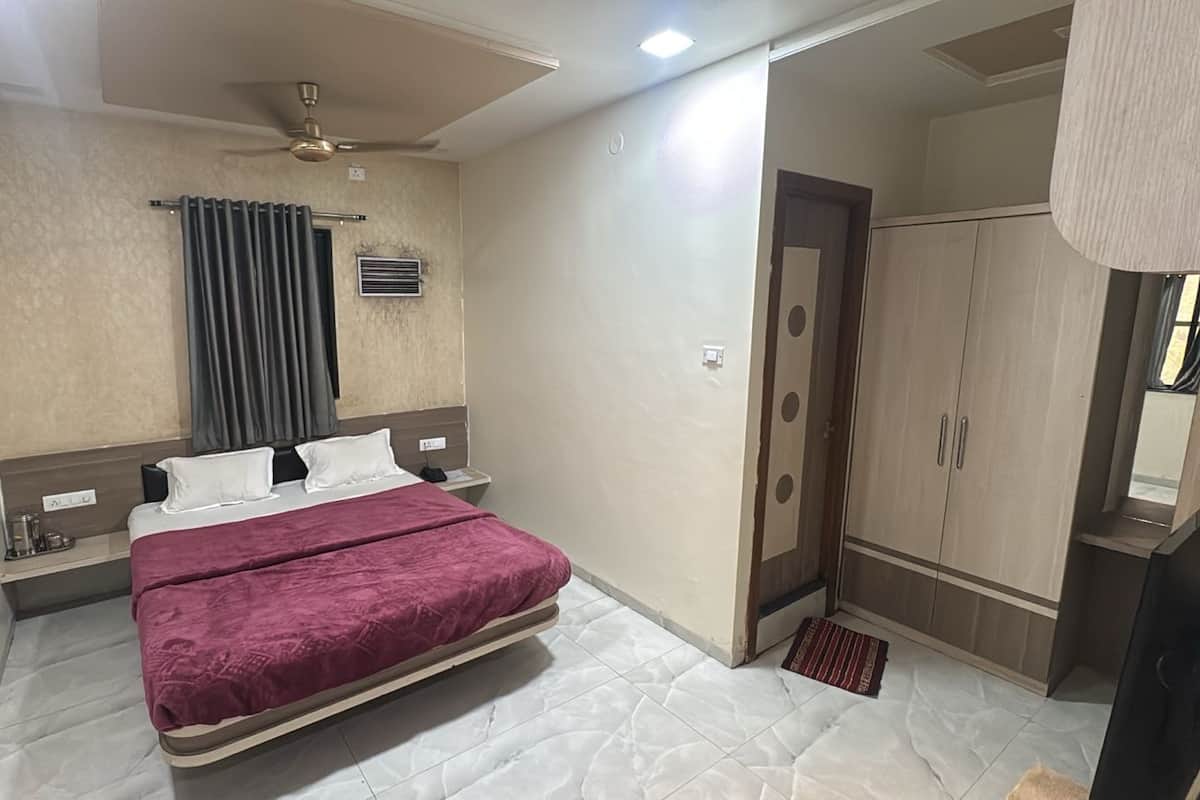 A hotel room with a bed, a ceiling fan, a wardrobe, and a bathroom door.