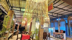 An indoor space with a high ceiling, hanging decorative elements, brick pillars, and a seating area with tables and chairs. - Top View Koh Rong (Koh Rong)