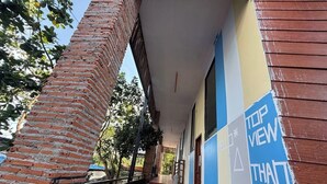 A covered outdoor corridor with a brick wall on one side and a building with a blue and yellow facade. - Top View Koh Rong (Koh Rong)