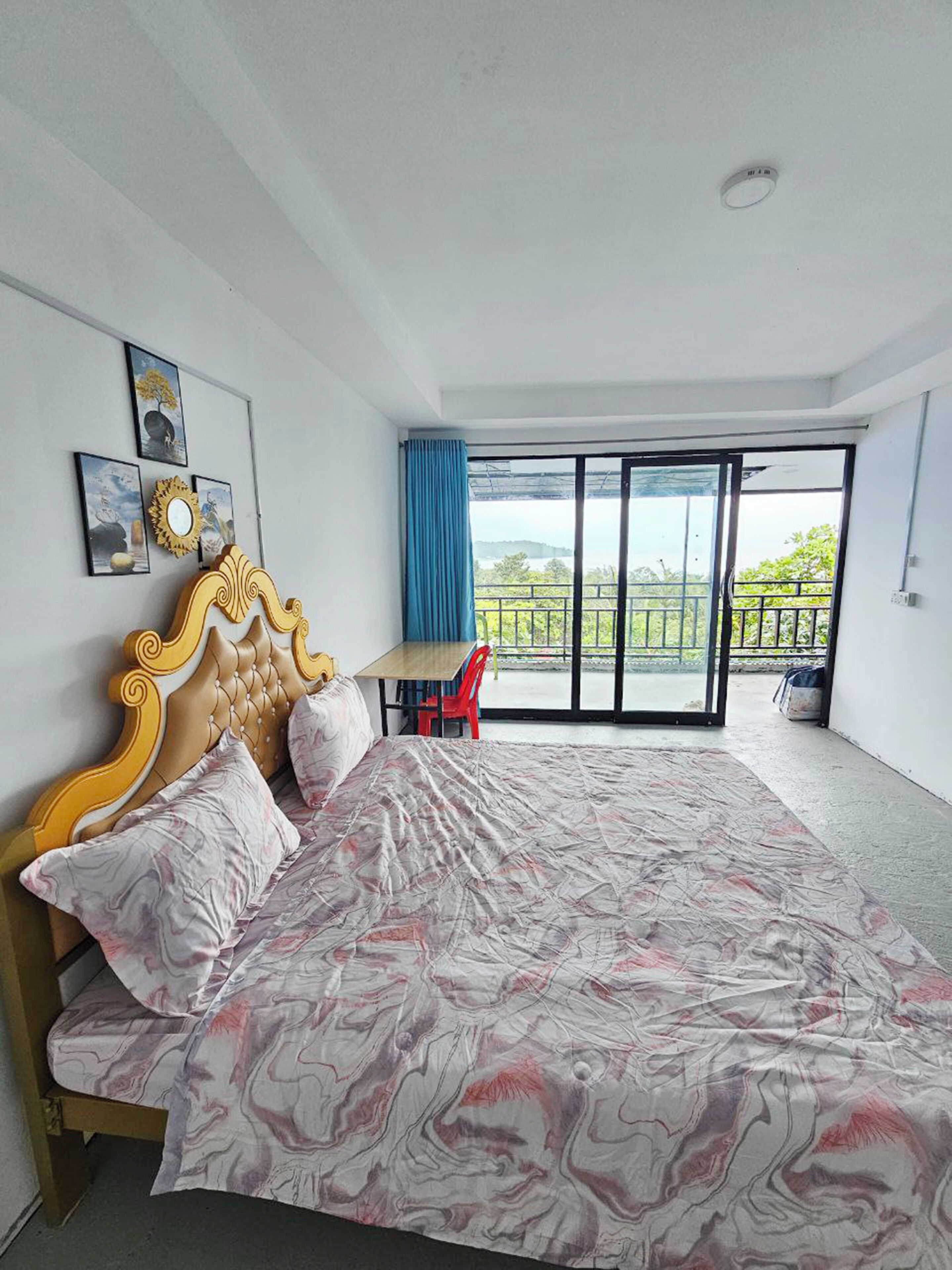 Un dormitorio con cama, escritorio y vistas a un balcón.