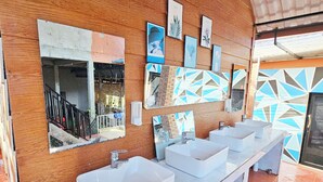 A modern bathroom with a long white sink counter, wooden walls, and various framed artworks. - Top View Koh Rong (Koh Rong)