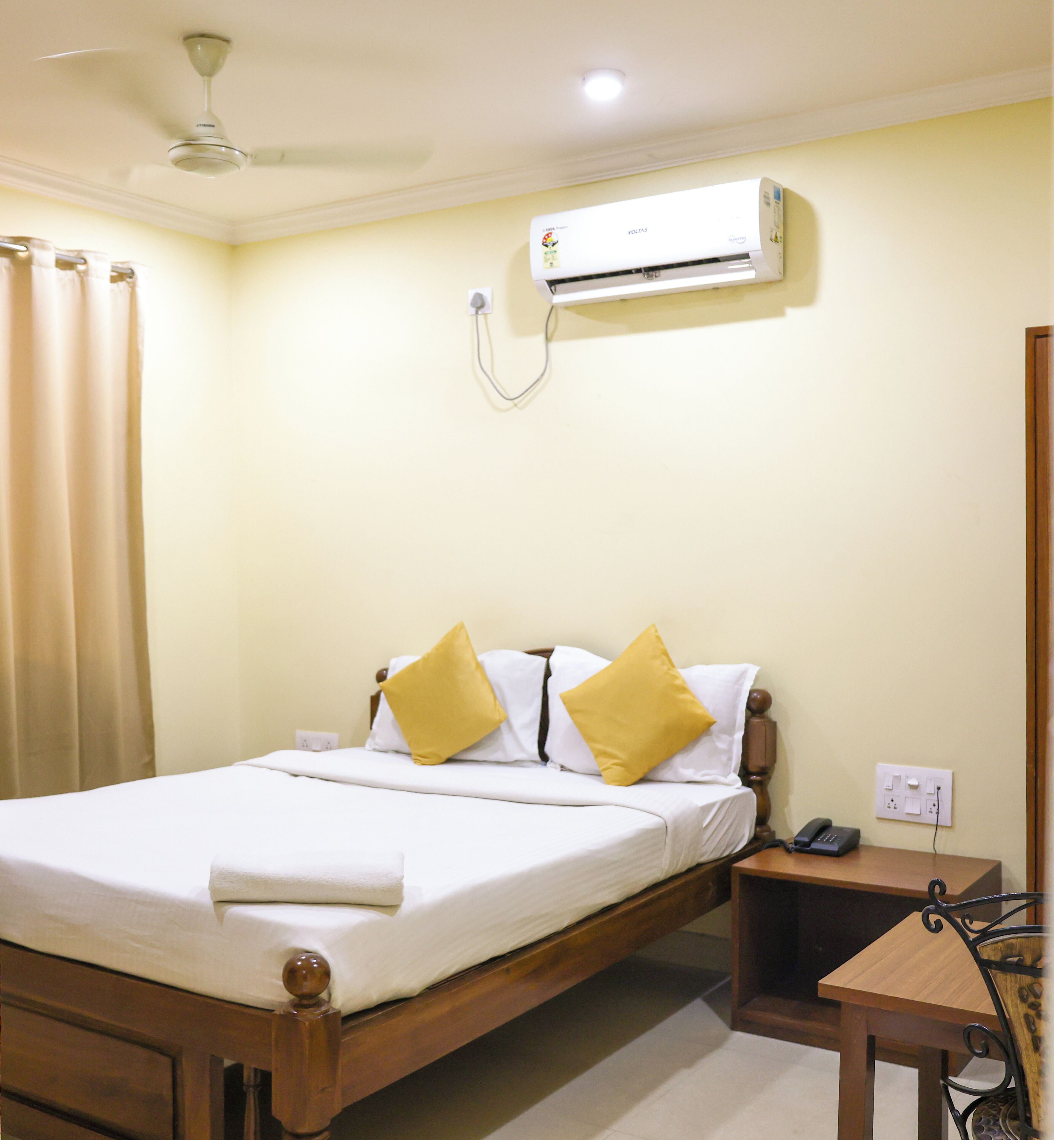Une chambre d’hôtel équipée d’un lit, d’une table de chevet et d’un appareil de climatisation fixé au mur.