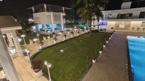 Un espace extérieur bien éclairé, comprenant une piscine, une pelouse et un chemin pavé.
