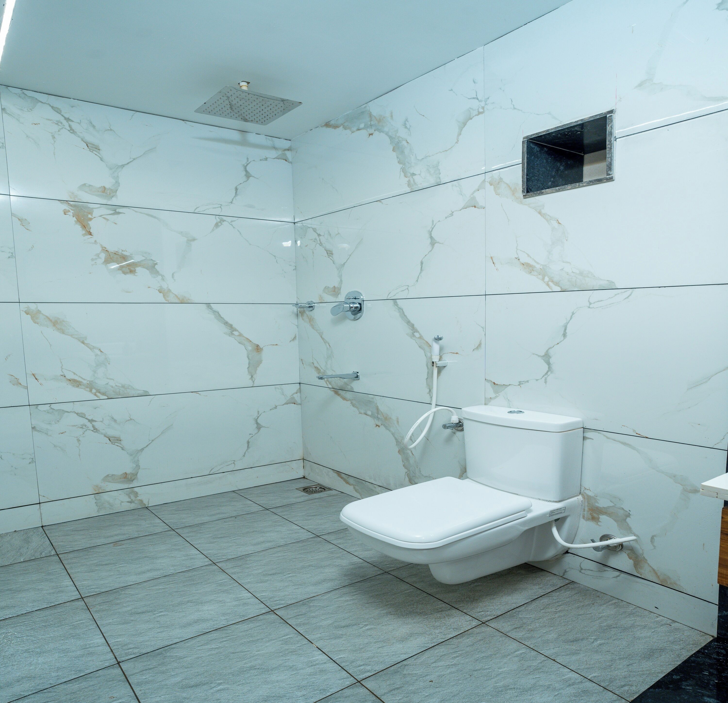 A bathroom with a toilet, shower, and a small window.