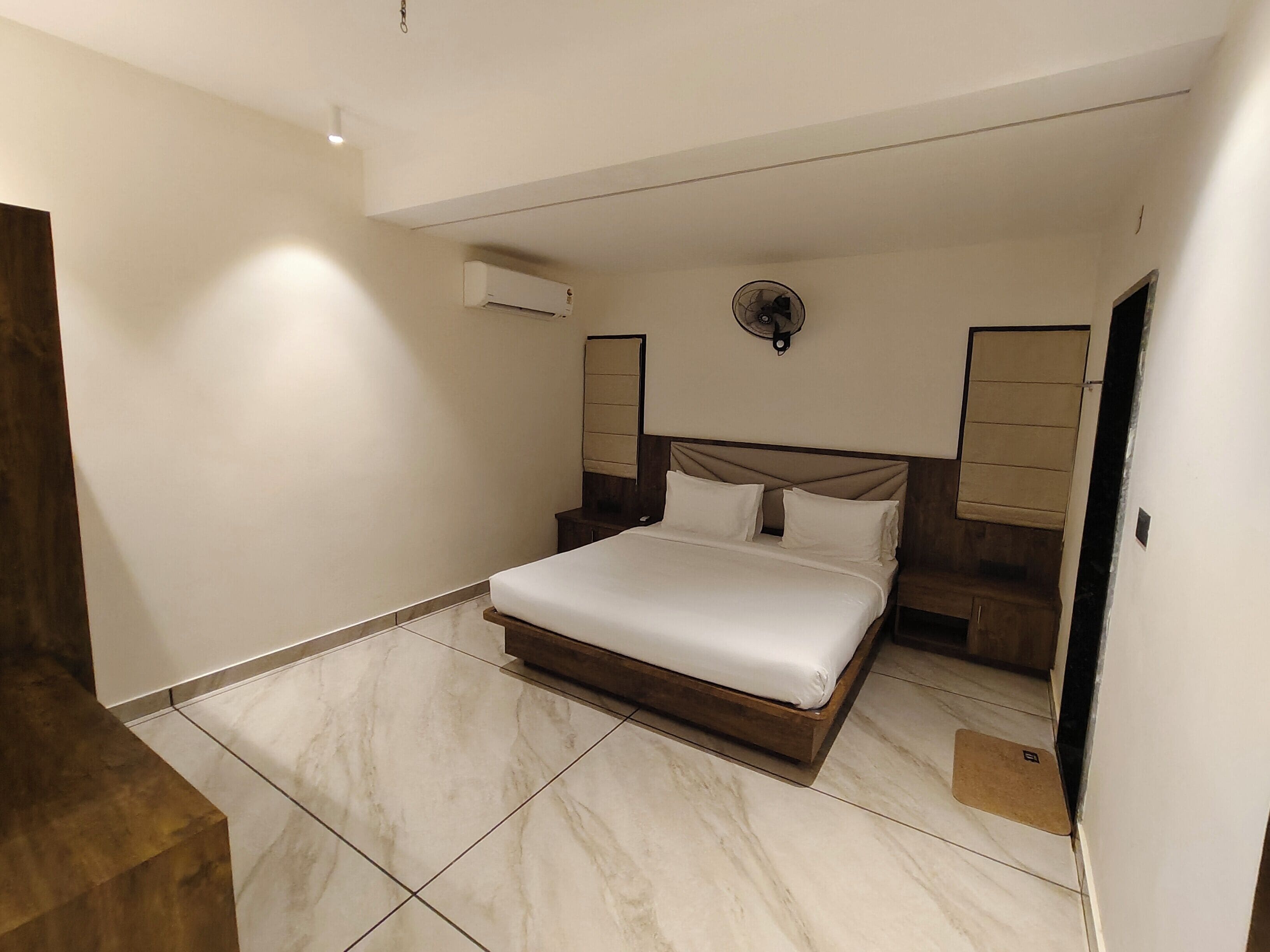 A modern bedroom with a large bed, a ceiling fan, and an air conditioning unit.