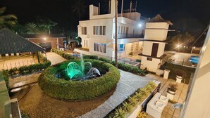 Une cour avec une fontaine, une piscine et un bâtiment moderne doté de balcons.