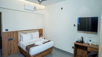 Una habitación de hotel con cama, escritorio, silla, televisor y ventilador de techo.