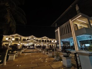 Un hotel de varios pisos con un patio central, mobiliario exterior y una iluminación moderna.