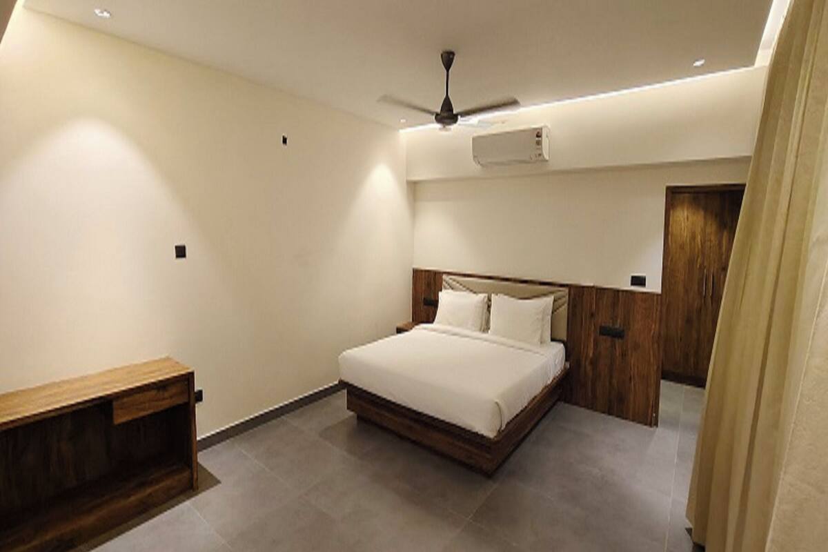 Een slaapkamer met een bed, een plafondventilator, een airconditioner en een houten bank.
