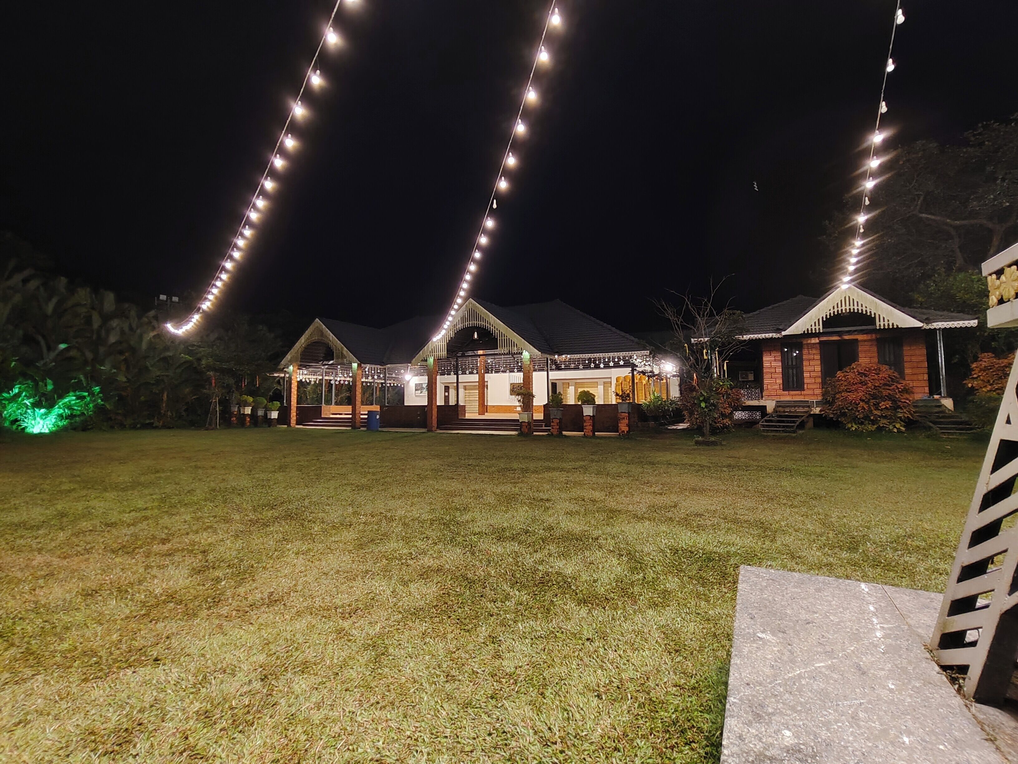Una casa con un porche bien iluminado y un patio cubierto de césped.