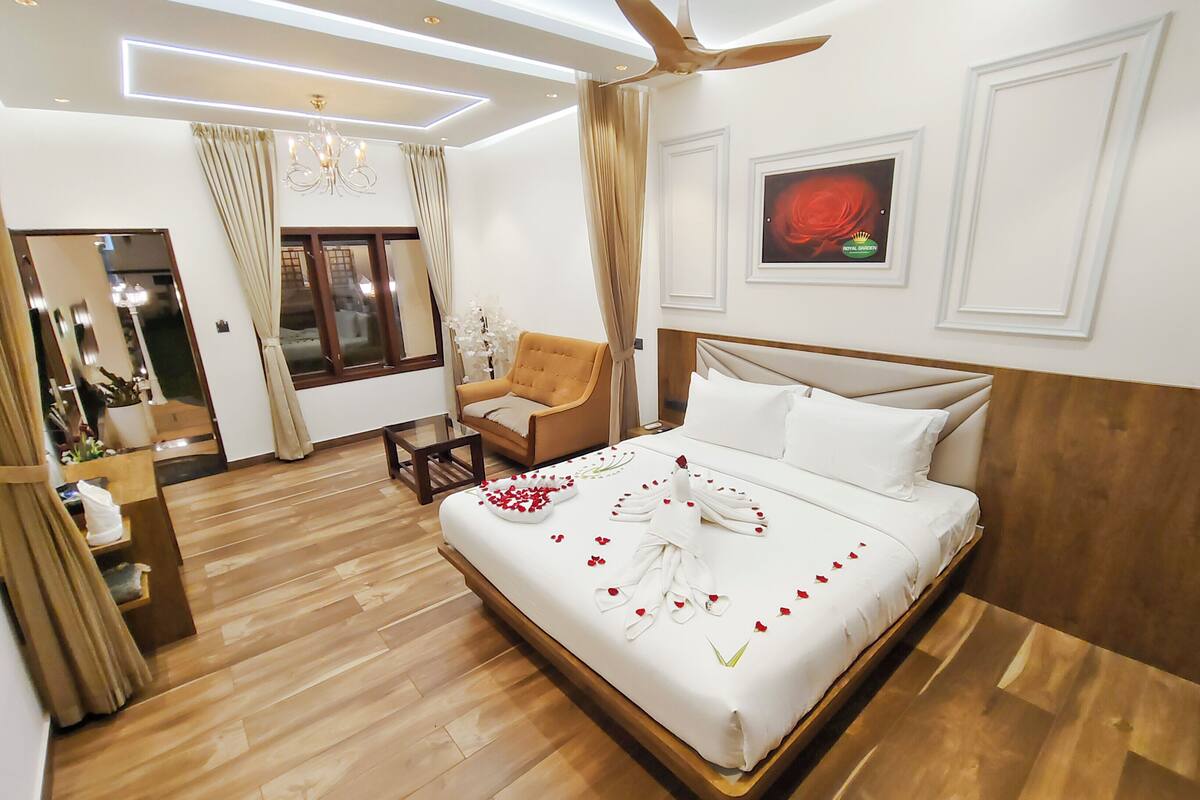 Een hotelkamer met een bed, een stoel, een plafondventilator en een raam.
