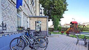 A brick building with a bicycle rental station and a playground with a slide and swings. - One bedroom Twin apartment in the center of Riga (Riga)