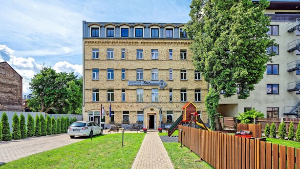 A multi-story building with a brick facade, a central entrance, and a playground area. - One bedroom Twin apartment in the center of Riga (Riga)