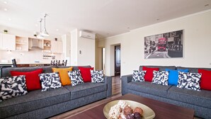 A modern living room with two grey sofas, colorful cushions, a wooden coffee table, and a kitchen in the background. - Two bedrooms, Two double beds, 8 persons (Riga)