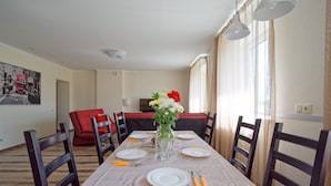 A dining area with a table set for four, chairs, a vase with flowers, and a painting on the wall. - Two bedrooms, Two double beds, 8 persons (Riga)