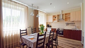 A modern kitchen with wooden cabinets, a built-in oven, and a sink. There is a dining area with a table set for two, chairs, and a vase with flowers. - Two bedrooms, Two double beds, 8 persons (Riga)