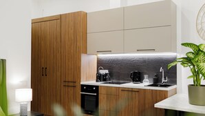 Eine moderne Küche mit Holzschränken, einem Einbauofen, einer Kaffeemaschine und einem Spülbecken.