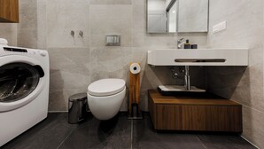 Ein modernes Badezimmer mit Waschmaschine, Toilette und einem Holzbadezimmerhocker mit Waschbecken.