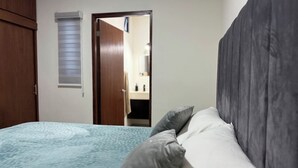 A bedroom with a bed, pillows, a wardrobe, and a door leading to a bathroom. - Spacious accommodation with excellent location (Mazatlán)