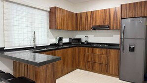 A modern kitchen with wooden cabinets, a black countertop, a stainless steel refrigerator, a microwave, and a coffee maker. - Spacious accommodation with excellent location (Mazatlán)