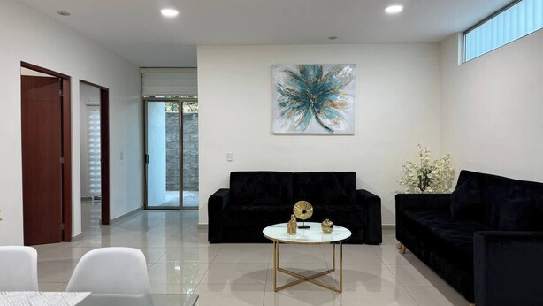 A modern living room with a black sofa, a round coffee table, and a painting on the wall. - Spacious accommodation with excellent location (Mazatlán)
