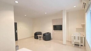 Ruime hotelkamer met een groot bed, een kleine tafel, twee stoelen en een aan de muur bevestigde televisie.