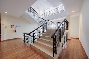Una escalera de varios niveles con barandillas negras y peldaños beige, que conduce a un segundo piso.